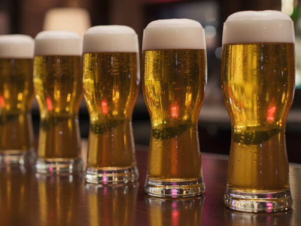 a line of ipa craft beer glasses on a bar rail lined up.