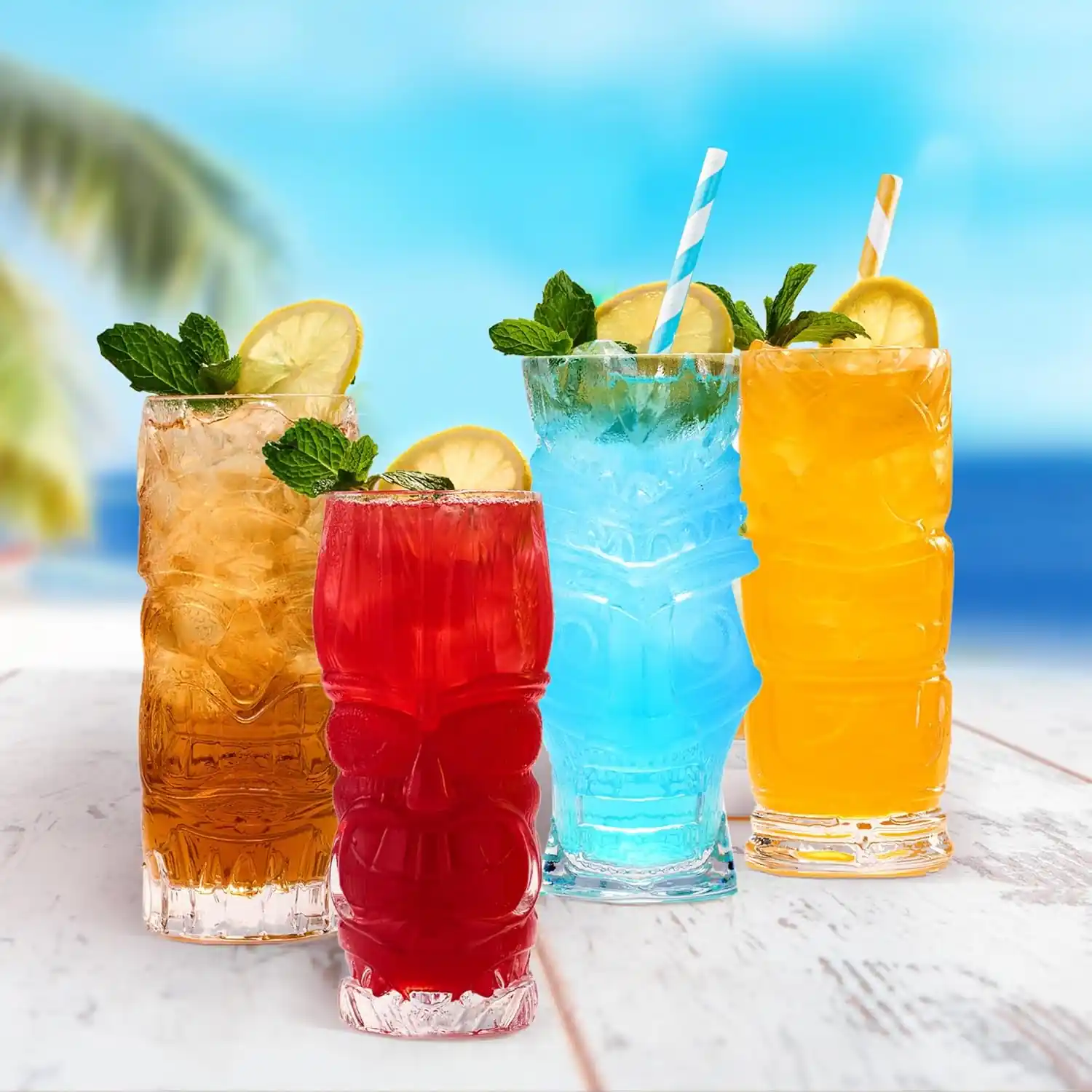 set of 4 clear tiki glasses each with 16oz beverage capacity on a beach.